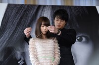 桐谷美玲（手前）にブルガリのネックレスを着ける鈴木伸之（奥）。