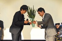 入江悠（右）から深谷ねぎを受け取る大森南朋（左）。