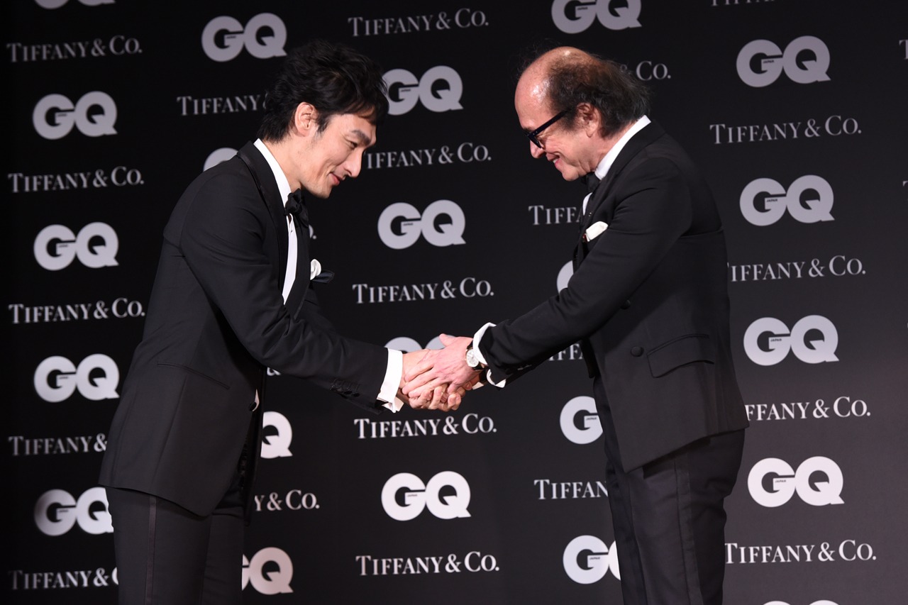 「GQ JAPAN」の鈴木正文編集長と握手を交わす草なぎ剛（左）。