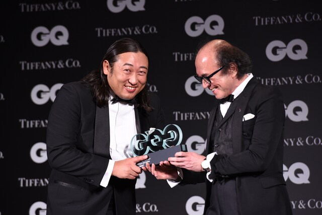 「GQ JAPAN」の鈴木正文編集長（右）からトロフィーを受け取るロバート秋山（左）。