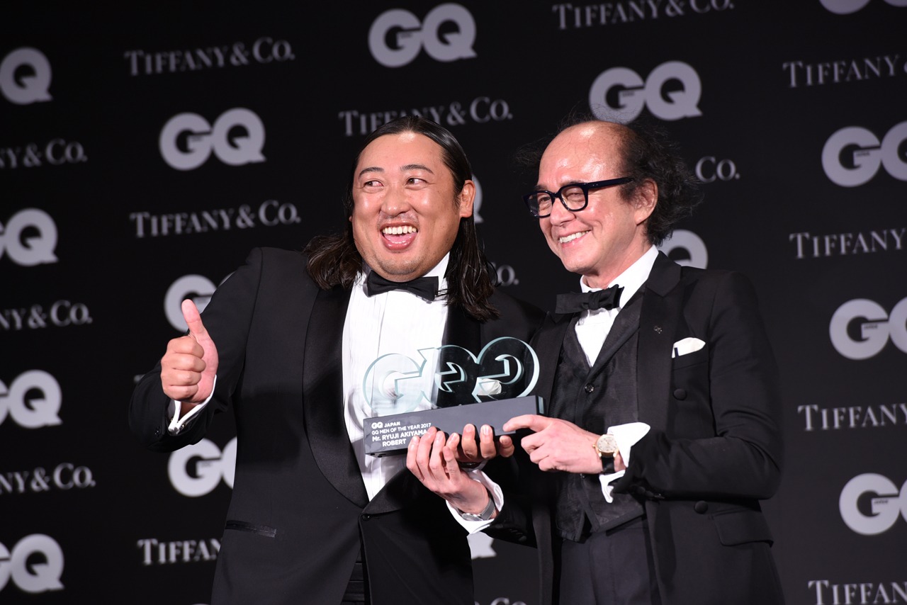 「GQ JAPAN」の鈴木正文編集長からトロフィーを受け取ったロバート秋山。