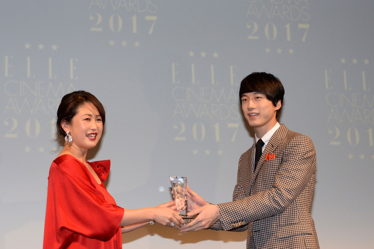 坂口健太郎（右）がELLE編集長の坂井佳奈子（左）からトロフィーを受け取る様子。