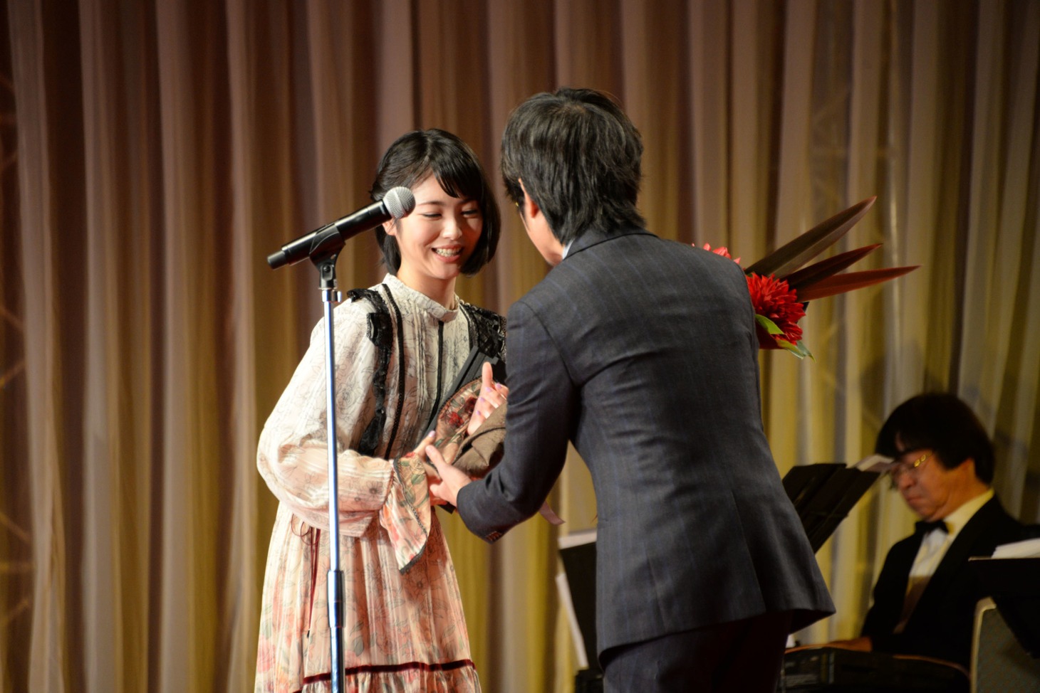 浜辺美波（奥）が月島翔（手前）から花束を受け取る様子。