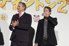 吹替版キャストを拍手で迎え入れるヒュー・ボネヴィル（左）と、水を飲むヒュー・グラント（右）。