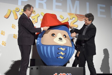 パディントンだるまに帽子をかぶせたヒュー・ボネヴィル（左）と、ヒュー・グラント（右）。