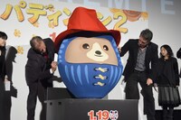 パディントンだるまにサインを入れるヒュー・ボネヴィル（左）と、ヒュー・グラント（右）。