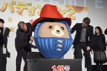 パディントンだるまにサインを入れるヒュー・ボネヴィル（左）と、ヒュー・グラント（右）。