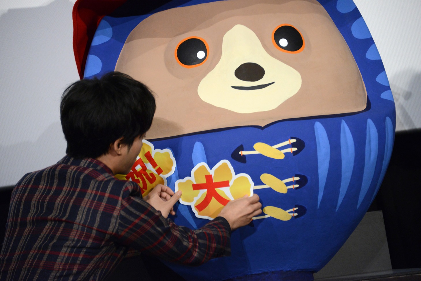 “パディントンだるま”にステッカーを貼る松坂桃李。