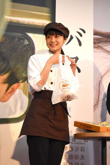 くまさんパンが入った袋を持つ深川麻衣。