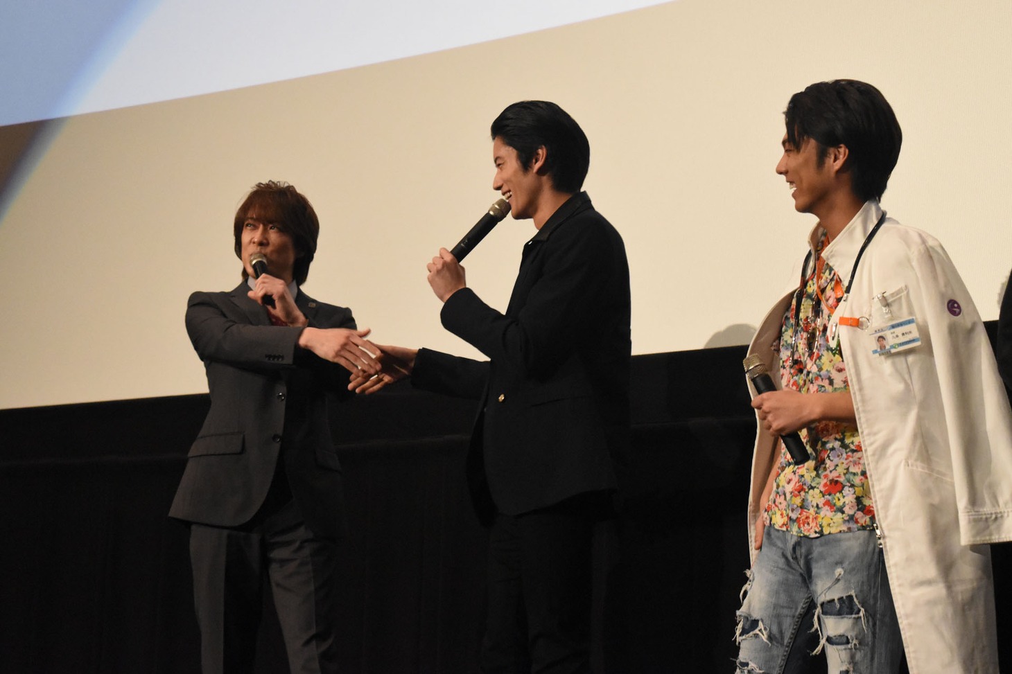 握手を交わす貴水博之（左）と岩永徹也（中央）。