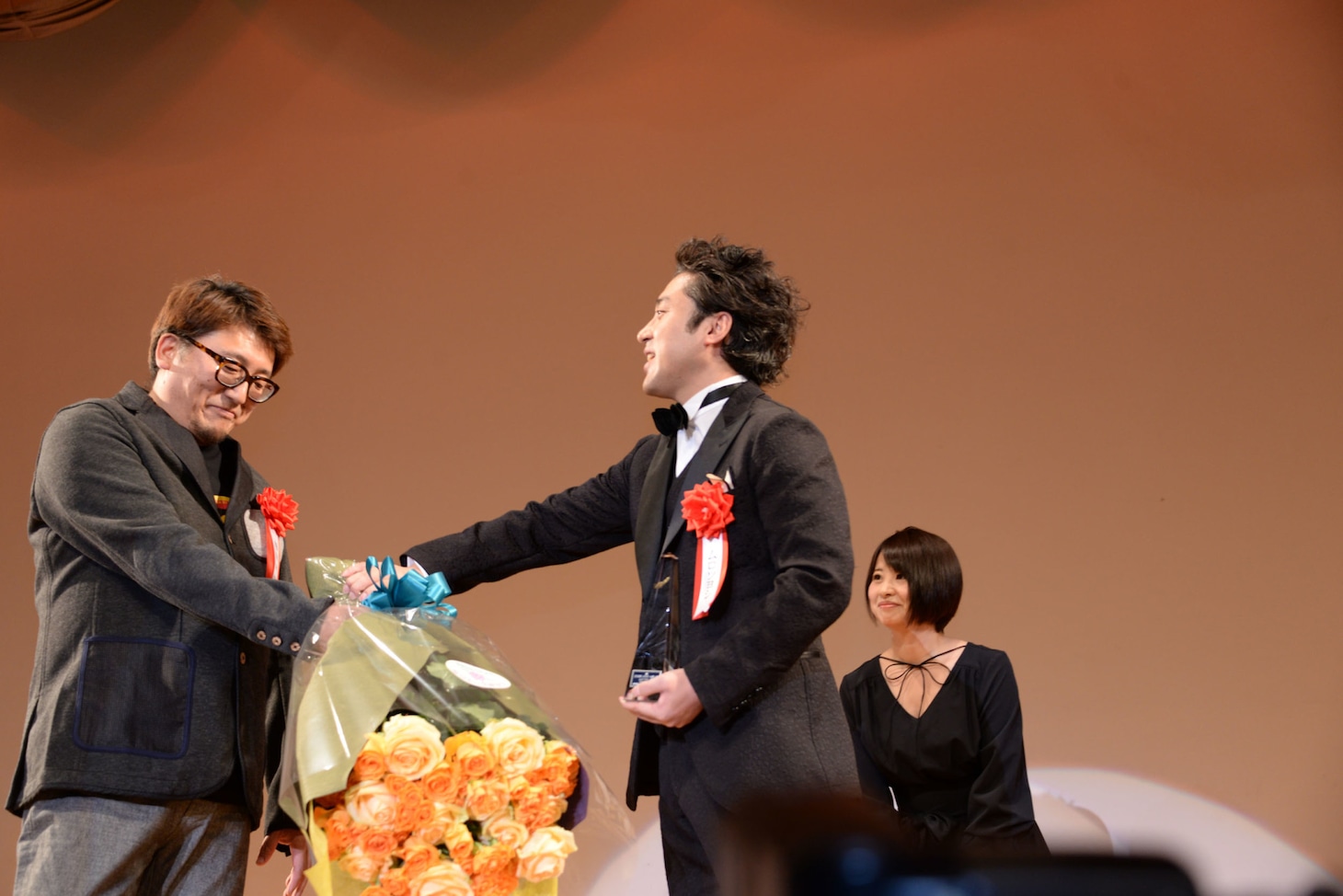 ムロツヨシ（右）に渋々花束を渡す福田雄一（左）。