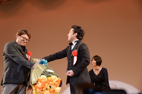 ムロツヨシ（右）に渋々花束を渡す福田雄一（左）。