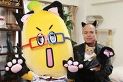 左から猫仕様のBSナナナ（BSナナニャ）、猫耳を着けて猫を抱く田中要次。