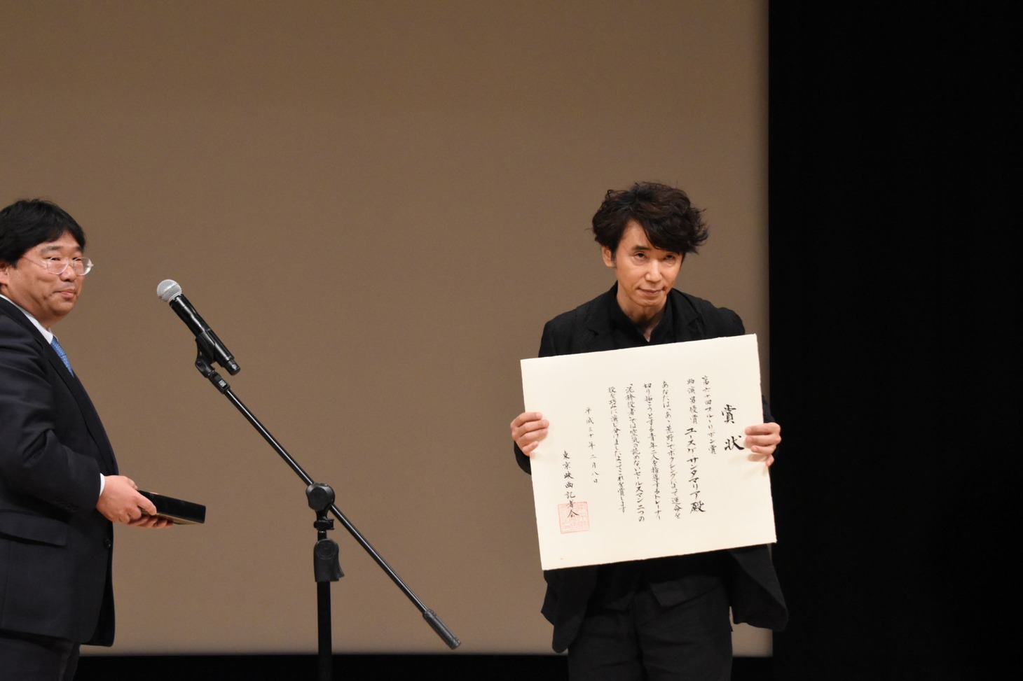賞状を見せるユースケ・サンタマリア。
