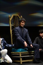 椅子の上で胡坐をかこうとする阿部寛。