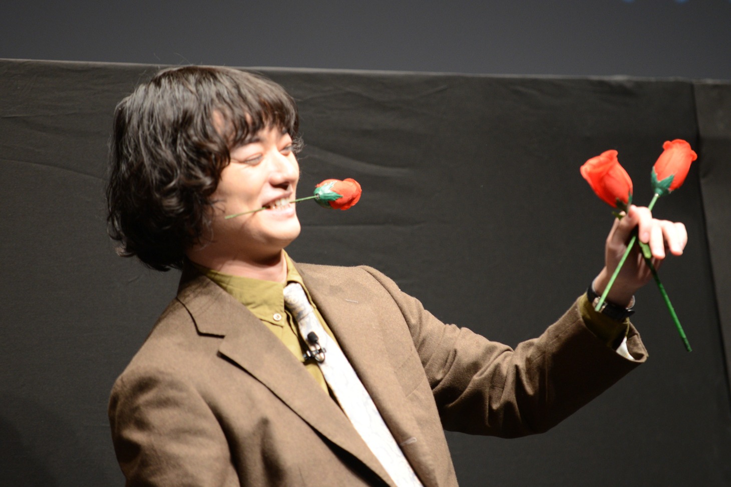 布の中から出したバラをくわえる染谷将太。