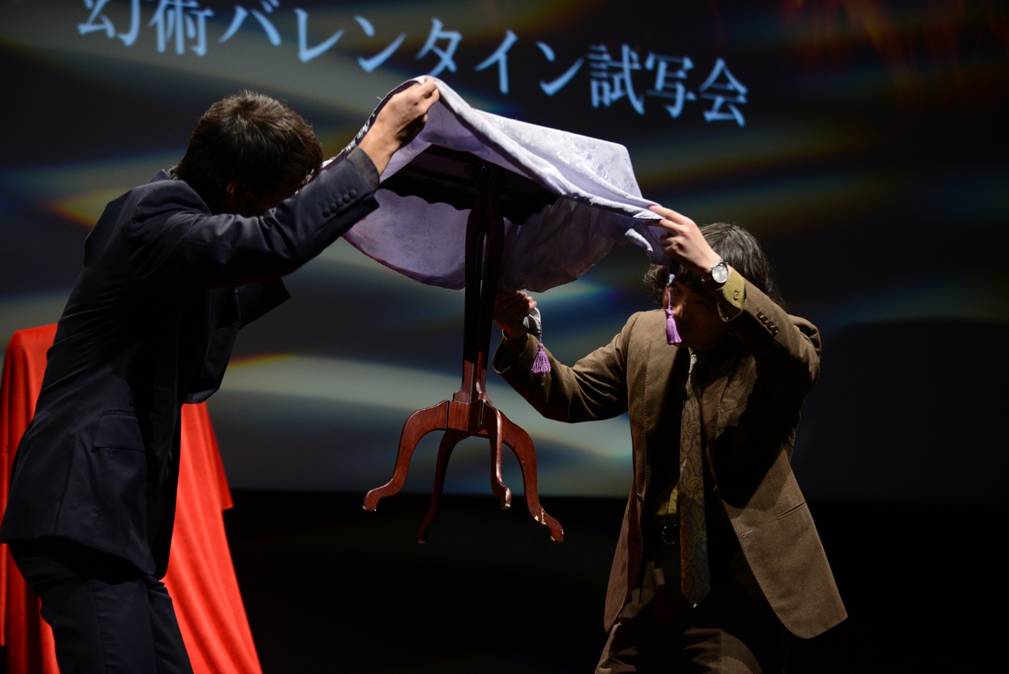 宙に浮く椅子の下をのぞき込む阿部寛（左）と染谷将太（右）。