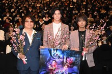 桃の花を持って写真撮影に応じる登壇者たち。左から鈴村展弘、岩永徹也、小野塚勇人。