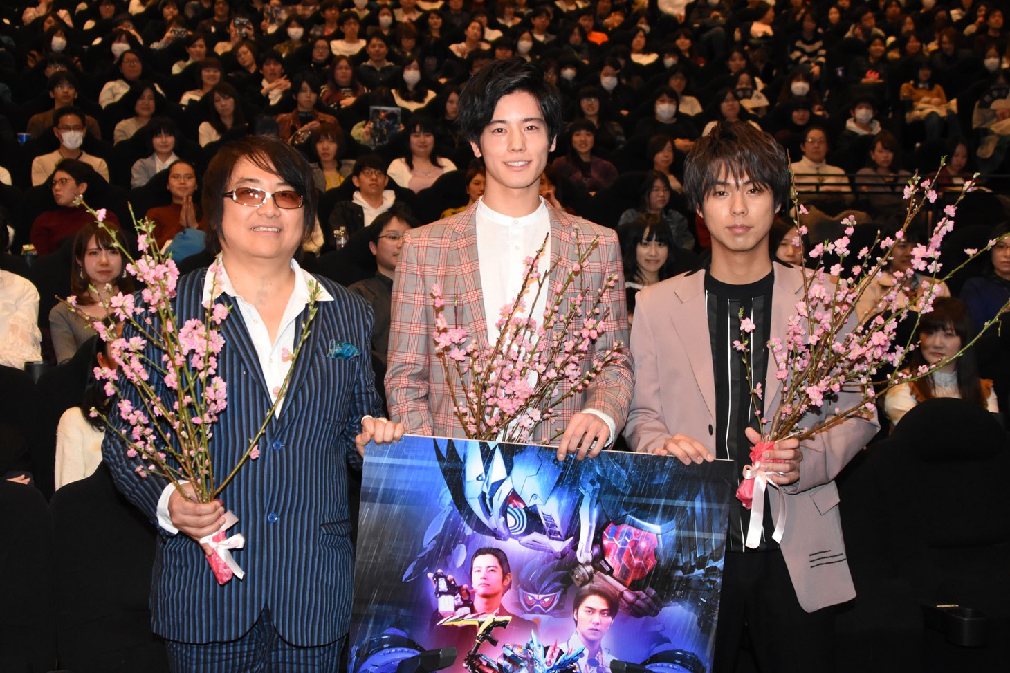 桃の花を持って写真撮影に応じる登壇者たち。左から鈴村展弘、岩永徹也、小野塚勇人。