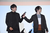 泰江和明（左）を見ずにマイクを手渡す輝山立（右）。