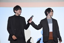 泰江和明（左）を見ずにマイクを手渡す輝山立（右）。