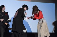 当選者にポスターを手渡す玉城裕規（左から2人目）。