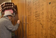 トークイベント前に劇場ドアにサインする大林宣彦。