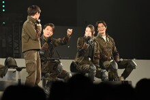 小林亮太に5円玉のネックレスを渡す俊藤光利（中央左）。