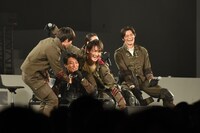 撮影の様子を再現するため、傘になりきる勝也（中央）。