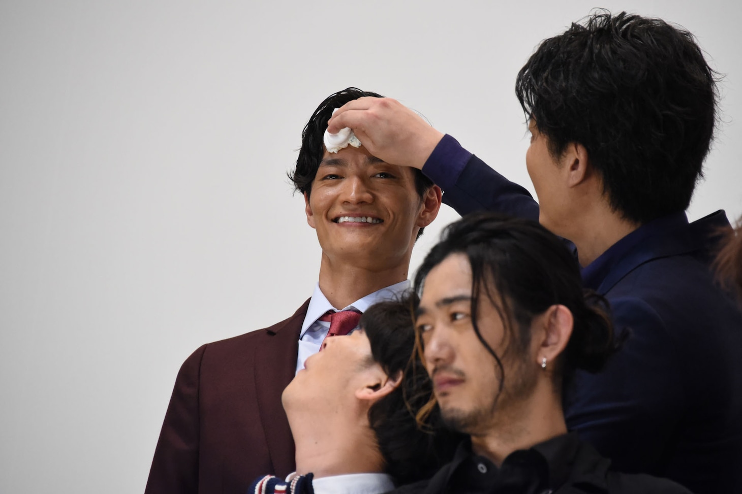 俊藤光利（後列右）に汗を拭いてもらう田邊和也（後列左）。