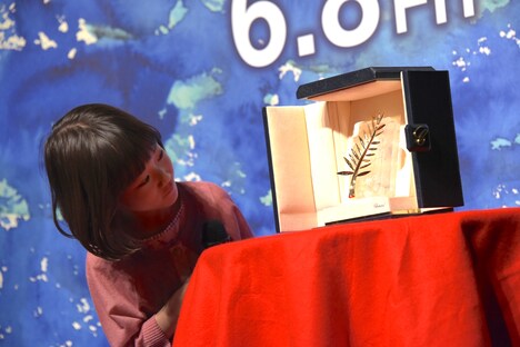 パルムドールのトロフィーをのぞき込む佐々木みゆ。