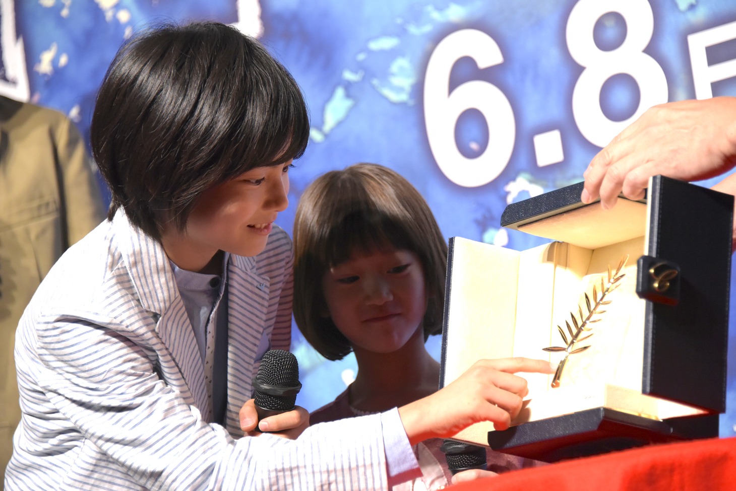 パルムドールのトロフィーに触れる城桧吏（左）、佐々木みゆ（右）。