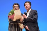 滝川広志（左）に花束を渡すため登壇した、千葉・八千代市長の服部友則（右）。