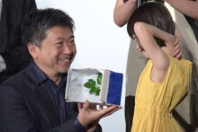 佐々木みゆ（右）から“手作りパルムドール”を渡された是枝裕和（左）。