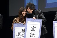 東出昌大が書いた放送禁止用語を耳打ちで教える綾野剛（右）。