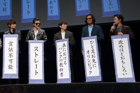 掛け軸を見せる登壇者たち。