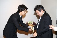 辻井伸行（右）に花束を手渡す山崎賢人（左）。