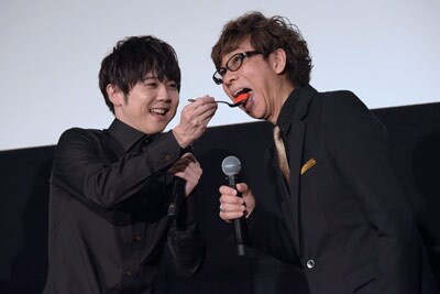 梶裕貴（左）が山寺宏一（右）にファーストバイトを行う様子。