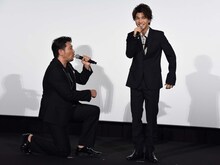 岩田剛典（右）に向かってひざまずく別所哲也（左）。