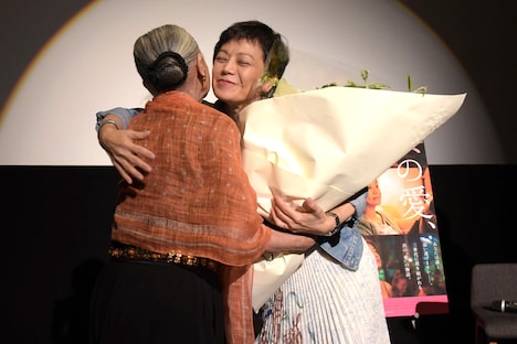 ワダエミ（左）から花束を受け取り、ハグを交わすシルヴィア・チャン（右）。
