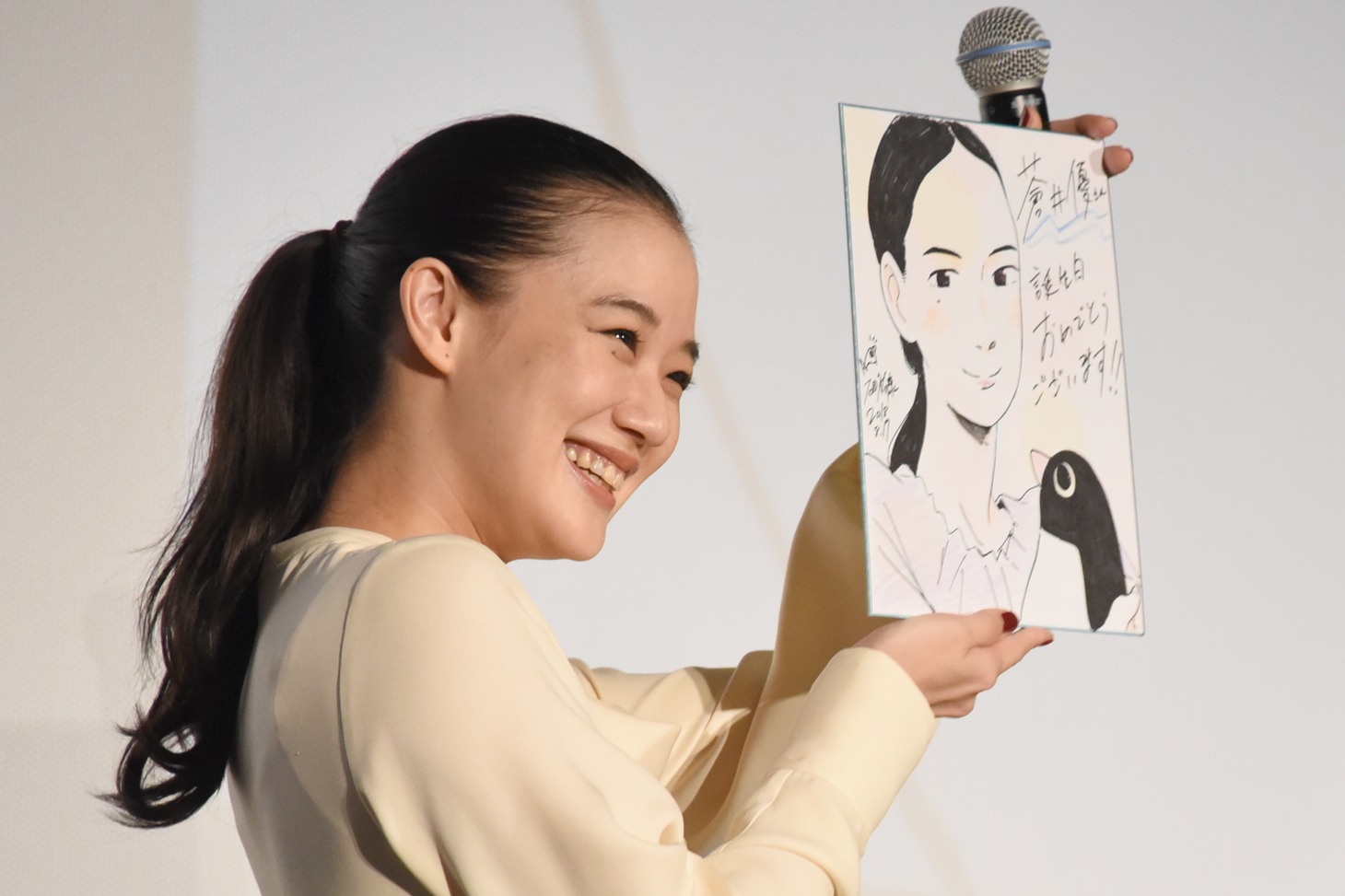 似顔絵の描かれた色紙を見せる蒼井優。