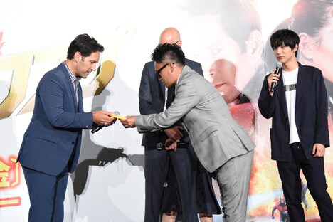 ポール・ラッド（左）にお守りを渡す宮川大輔（中央）。