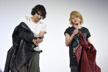 会場の暑さに衣装を脱ぎ出す藤田玲（左）と佐藤流司（右）。