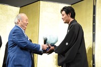 加藤一二三（左）から花束を受け取る松田龍平（右）。