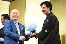 加藤一二三（左）から花束を受け取り、それまでの無表情を崩した松田龍平（右）。