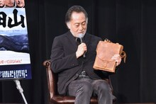 撮影に使用された雑嚢を見せる北大路欣也。