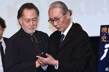 木村大作（右）のスマートフォンをのぞき込む北大路欣也（左）。