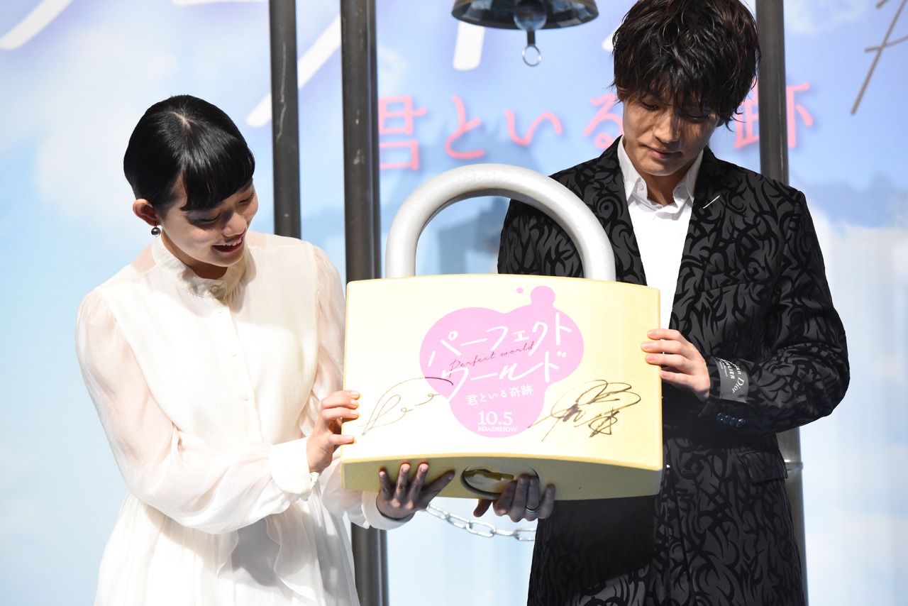 南京錠を持った杉咲花（左）と岩田剛典（右）。