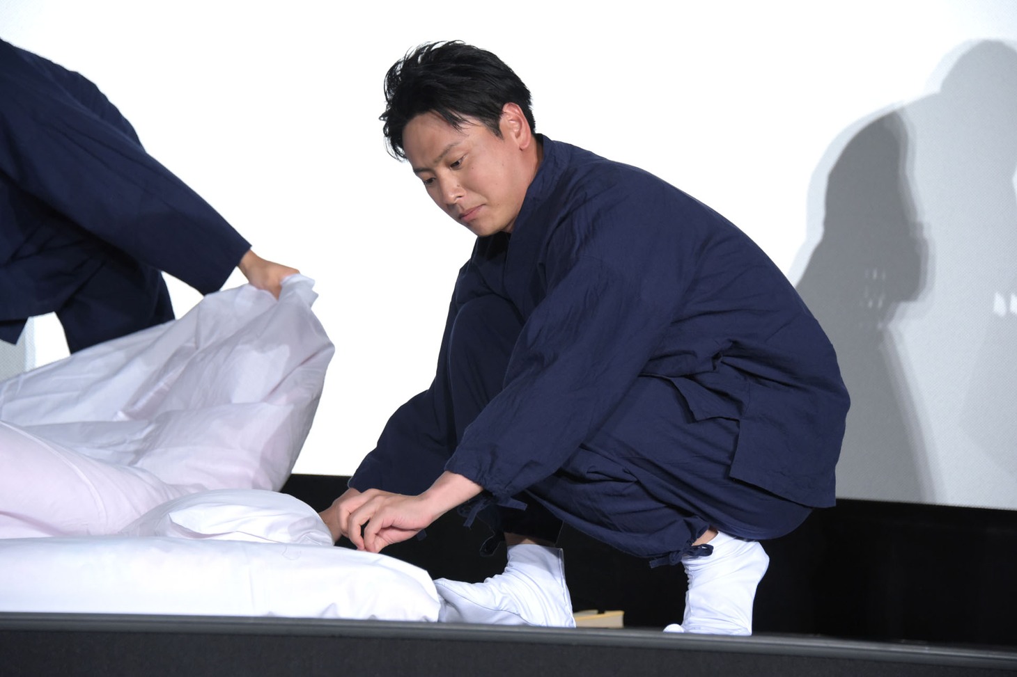 シーツの端をそろえる山下健二郎。