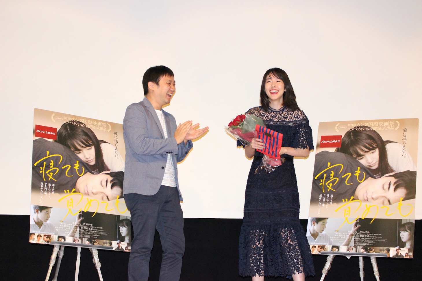 濱口竜介（左）から、バラの花束と牛腸茂雄の写真集を贈られた唐田えりか（右）。